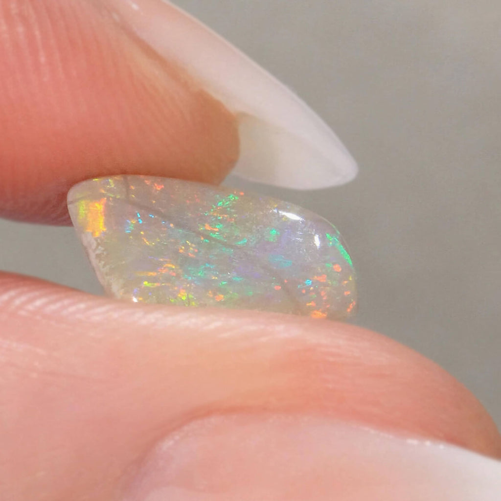 Side view of orange-green light opal cabochon