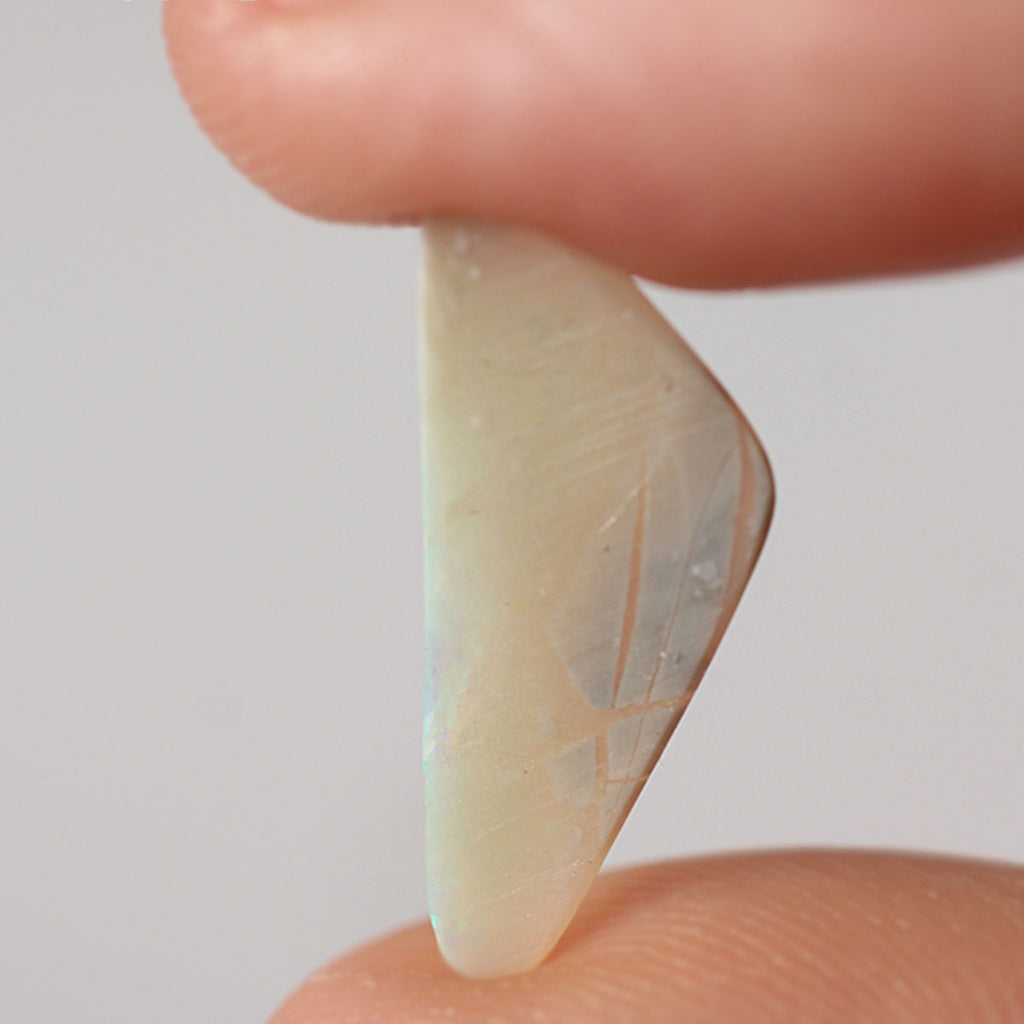 Light opal held between fingers for size reference