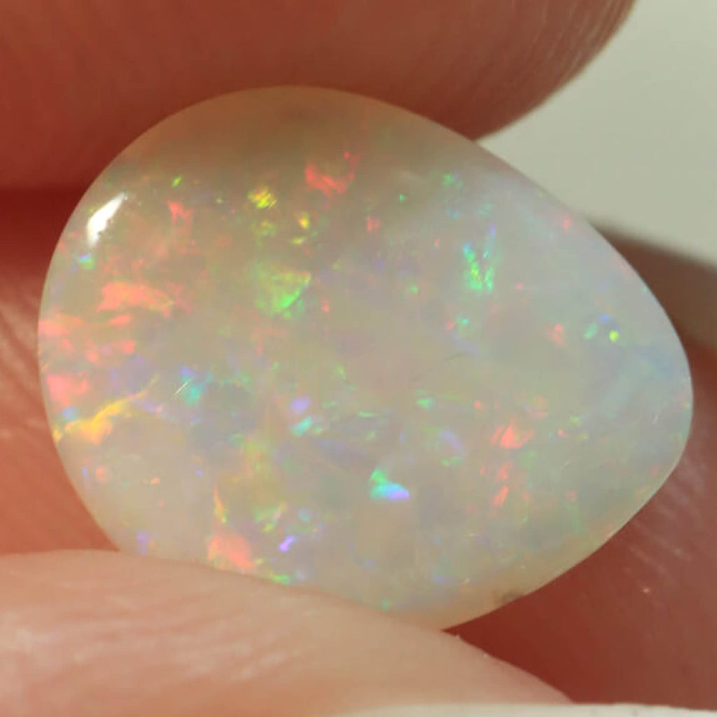 Light opal held between fingers for size reference