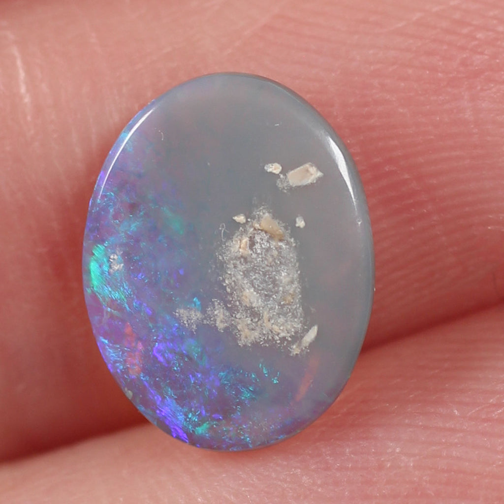 Dark crystal opal from Lightning Ridge held in hand to show scale