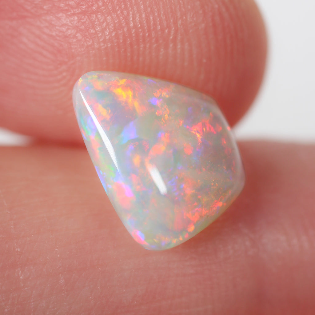 Side view of red-orange light opal cabochon