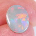Side view of orange-pink dark opal cabochon