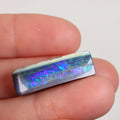Boulder opal held between fingers for size reference