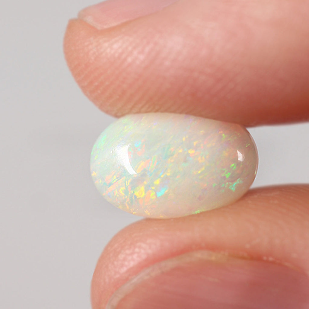 Light opal from Coober Pedy held in hand to show scale