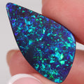Close-up of a blue and green opal stone held between fingers.