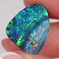 Multicolored opal stone held between fingers against a white background