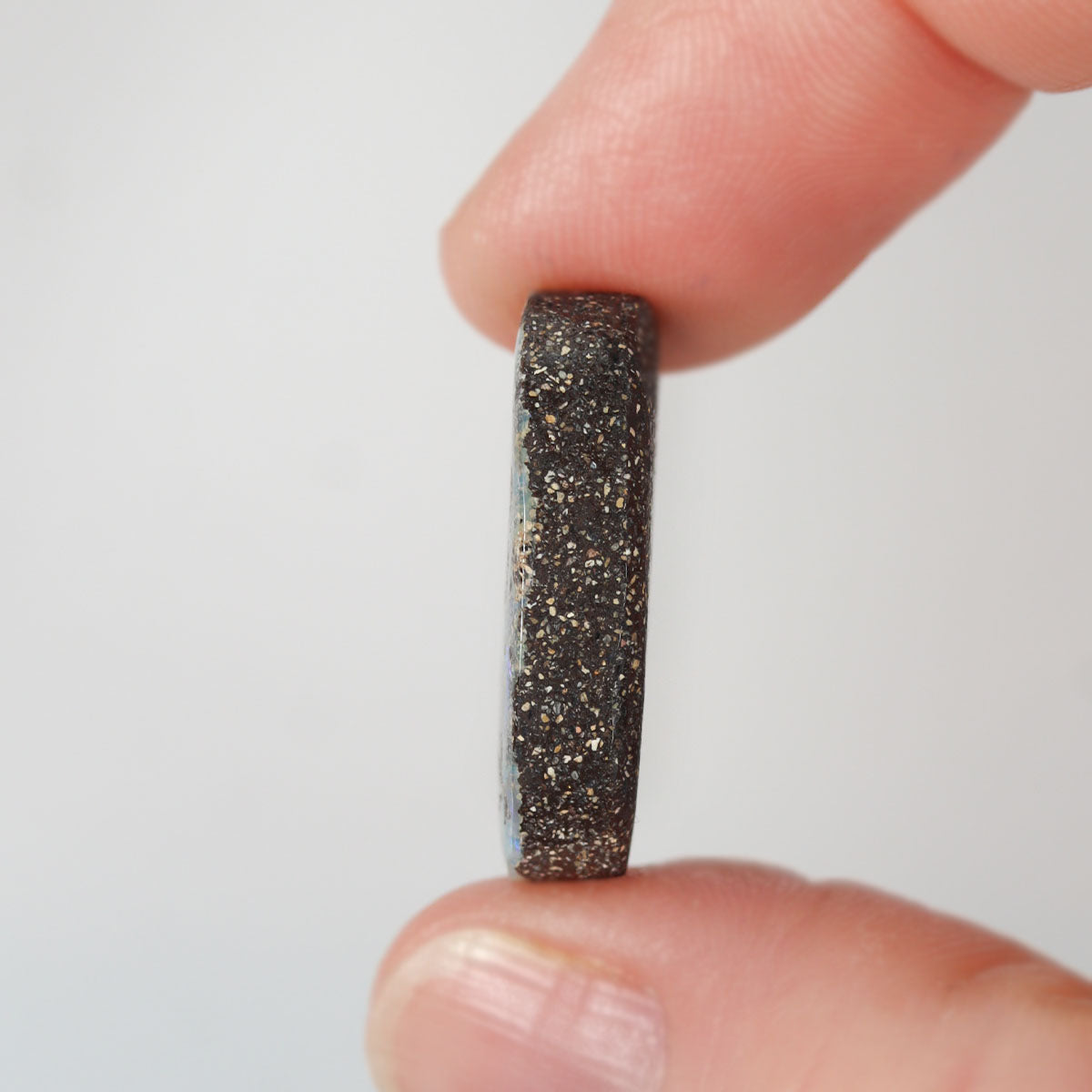 Boulder matrix held between fingers for size reference